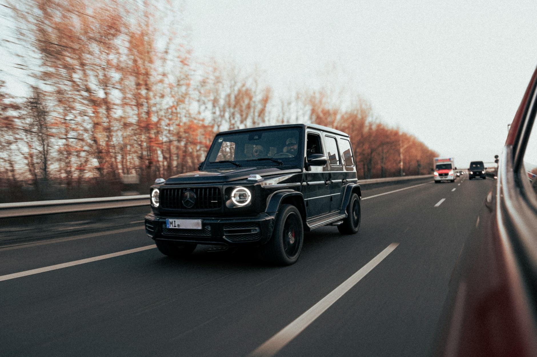 Czarny Cadillac Escalade jedzie autostradą w jesiennej scenerii