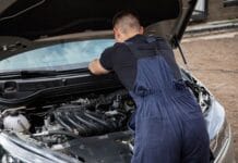 Mechanik naprawiający silnik samochodowy na zewnątrz w słoneczny dzień