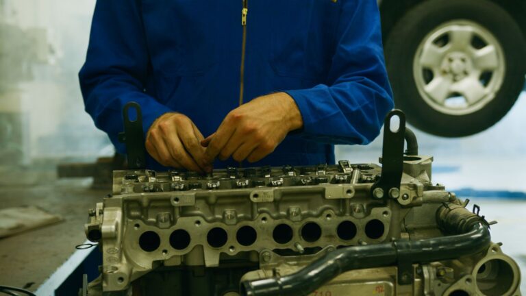 Mechanik naprawiający silnik samochodowy w warsztacie